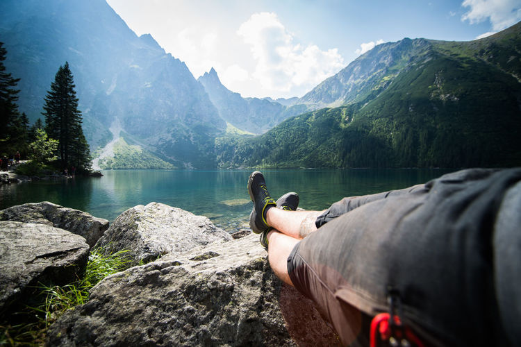 People looking at lake against mountain range