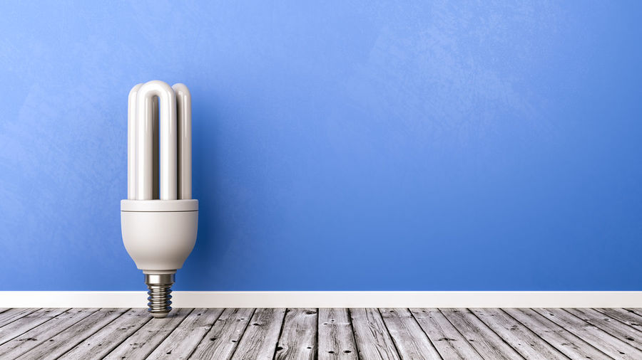 Close-up of lamp on table against blue wall