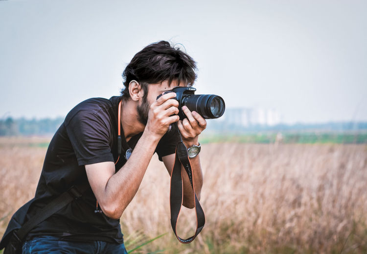 Young man photographing on field