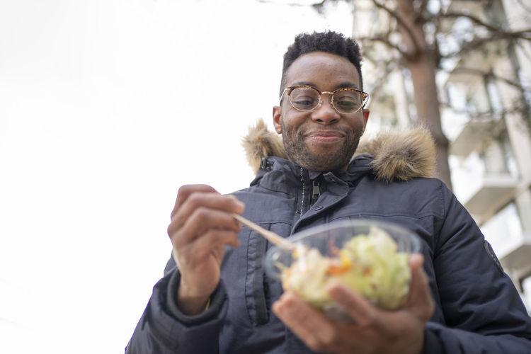 Smiling man with eyeglasses having salad during winter