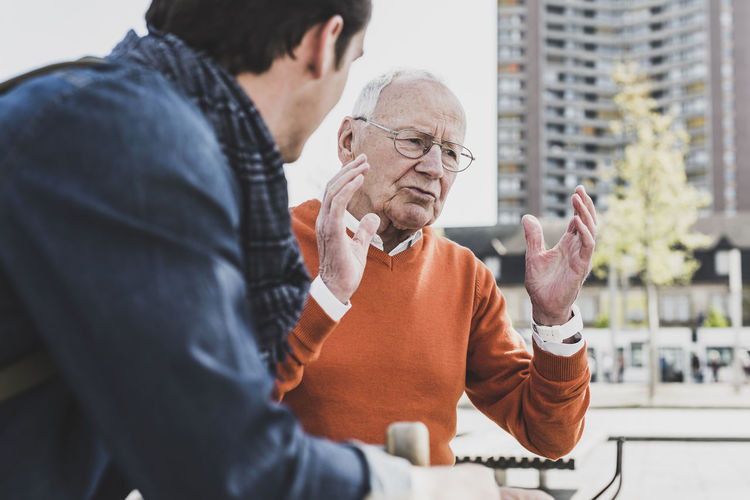 Senior man talking to adult grandson outdoors