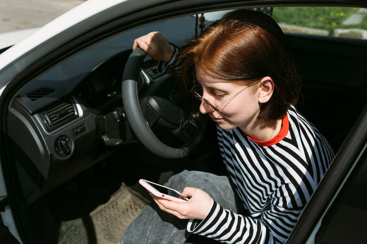 Young woman using mobile phone while sitting in car