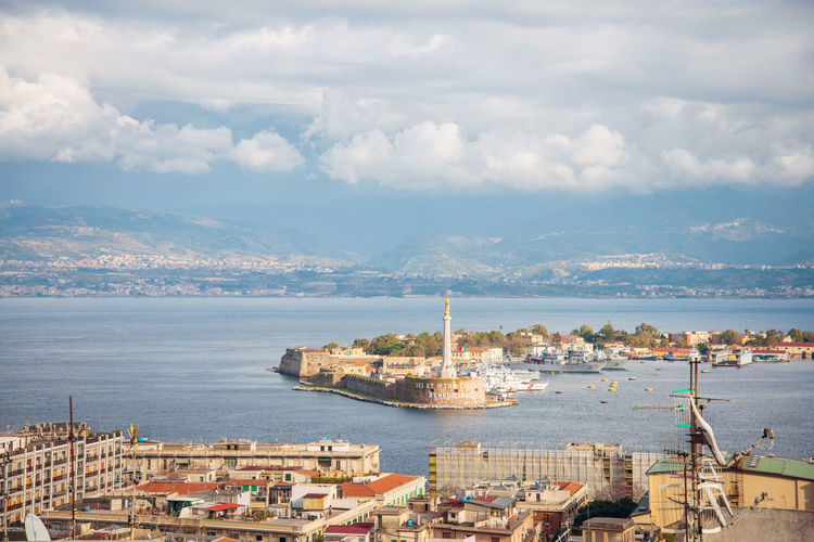 Aerial view of buildings by sea against sky