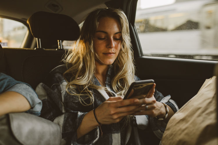 Young woman using phone while sitting in car