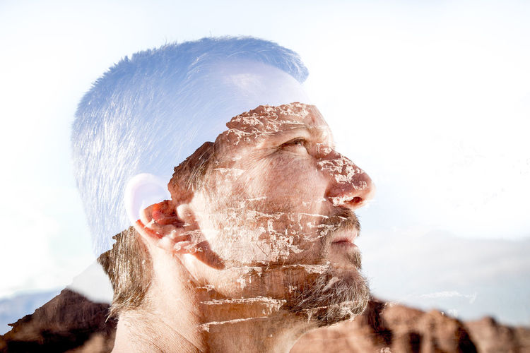 Double exposure of man and mountains against clear sky