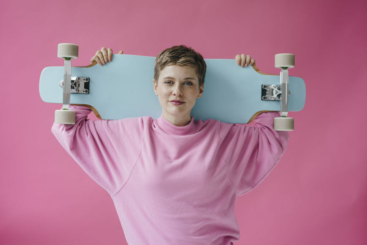 Portrait of woman in pink holding skateboard