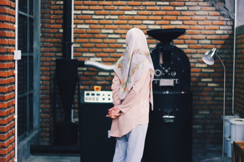 Rear view of woman walking against brick wall