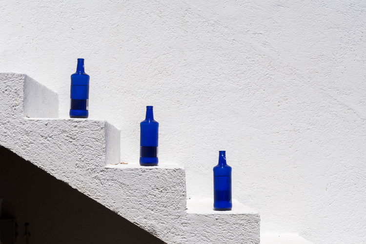 Blue bottles against white wall