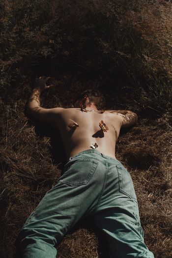 High angle view of shirtless man lying on field
