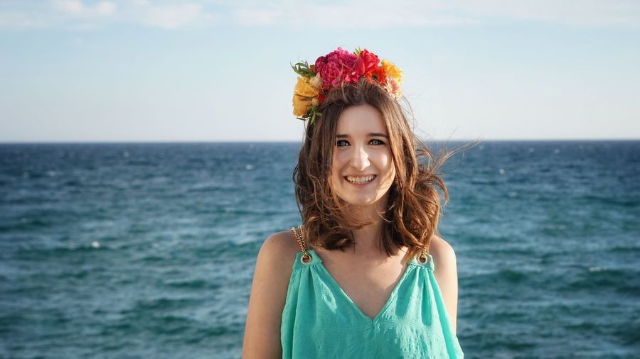 Portrait of a smiling young woman standing against sea