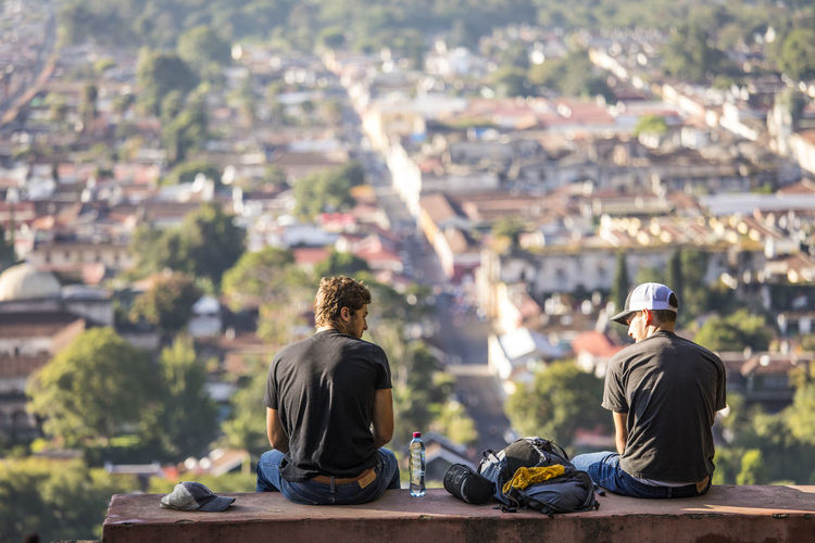 Tourists sit on bench at hill of the cross overlooking antigua