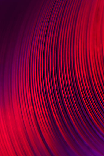 Closeup of coiled metal spring rings in a compressed state in red neon light
