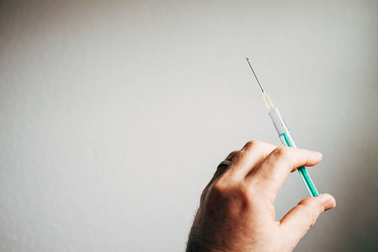 Hand holding syringe needle with droplet