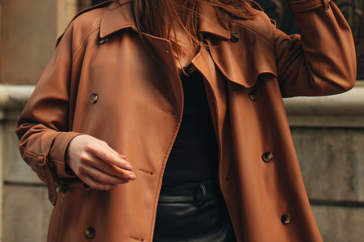 Cropped figure of young woman wearing stylish brown overcoat street casual autumn concept. 