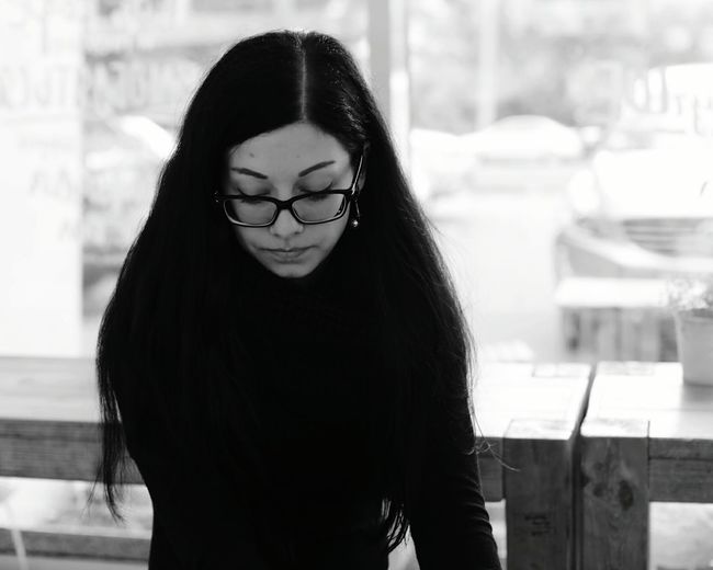 Depressed woman wearing eyeglasses while sitting at cafe