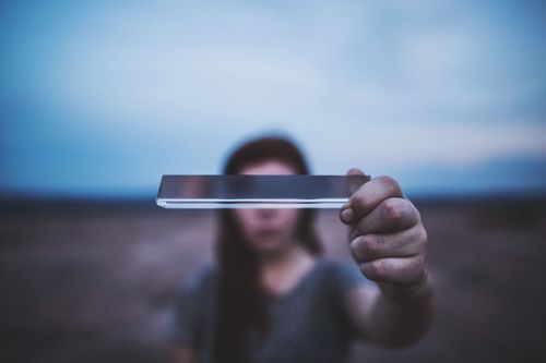 Close-up of woman holding smart phone against sky