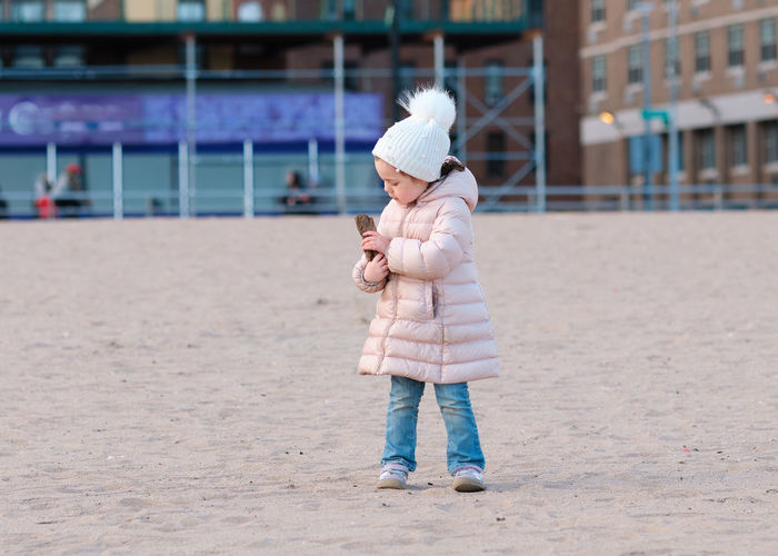 Little girl is playing on an empty beach on a cold day