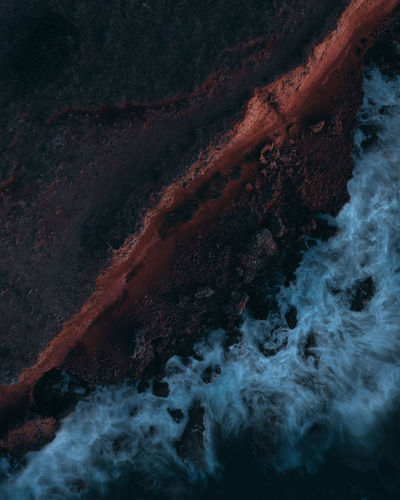 Aerial shot of waves crushing into the shore at dusk. 