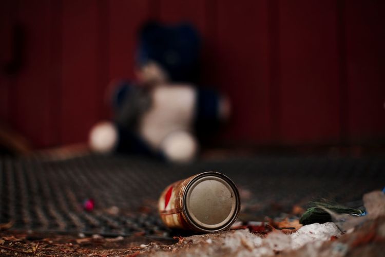 Close-up of can against abandoned stuffed toy