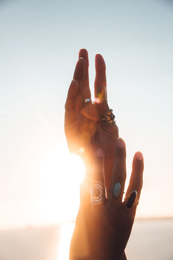 Hands against sky during sunset