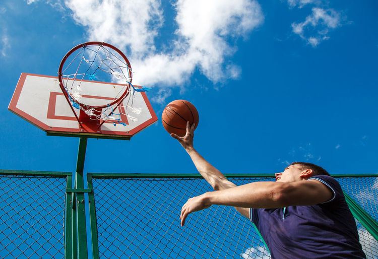Low angle view of man playing basketball sky