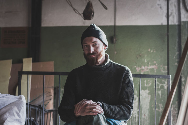 Portrait of smiling man wearing knit hat sitting indoors
