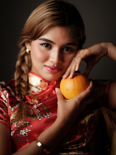 Close-up of young woman holding orange