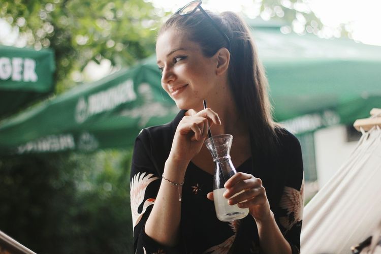 Smiling woman having drink outdoors
