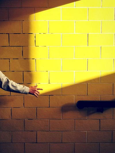 Human hand in the shadow against yellow wall light window