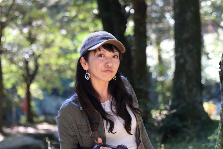 Portrait of woman wearing baseball cap against trees