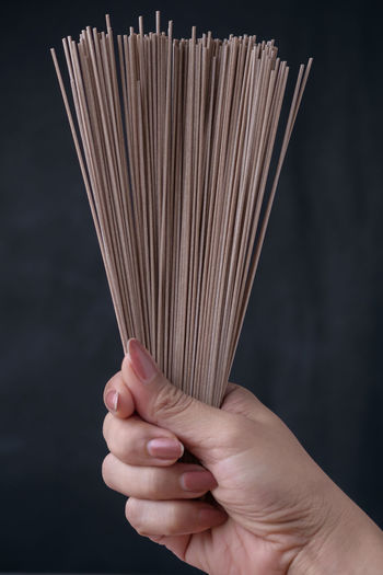 Cropped image of woman raw soba noodles against black background