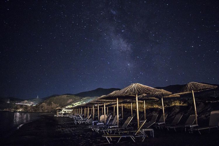 Thatched roofs and lounge chairs at beach at night