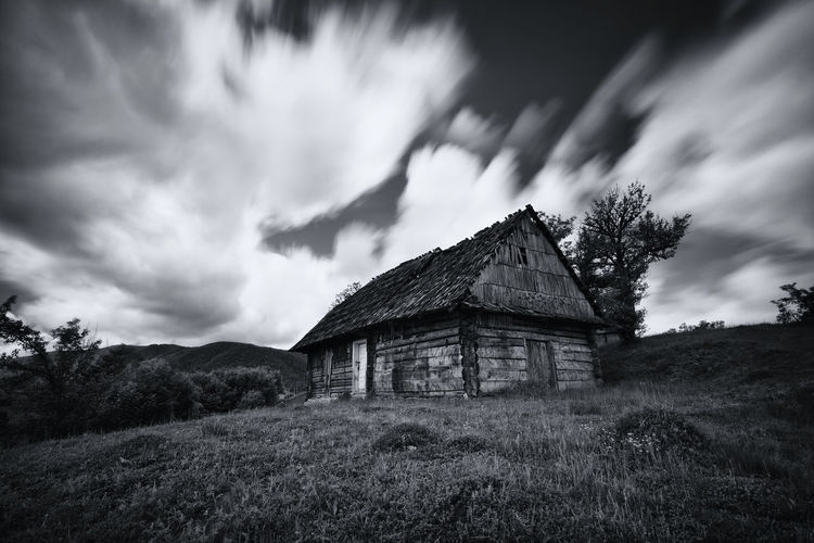 Old house on field against sky