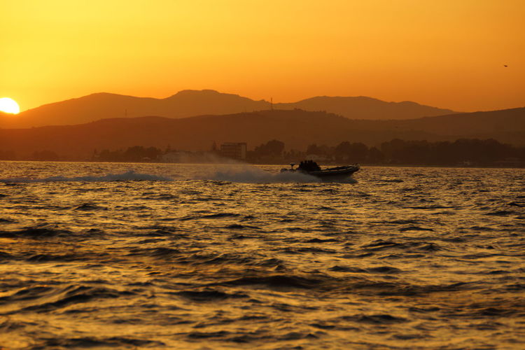 Silhouette boat in sea against sky during sunset
