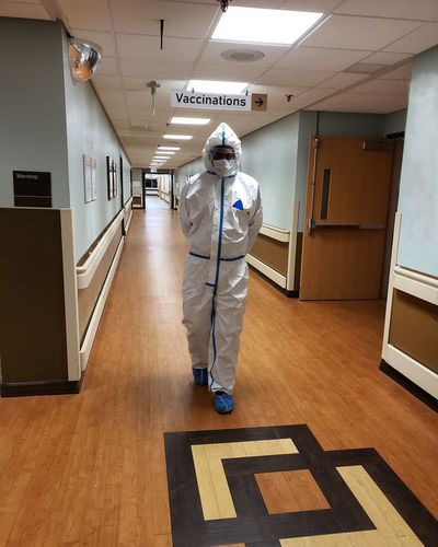 Full length of doctor wearing protective suit walking in hospital