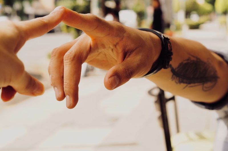 Cropped image of man touching human finger outdoors