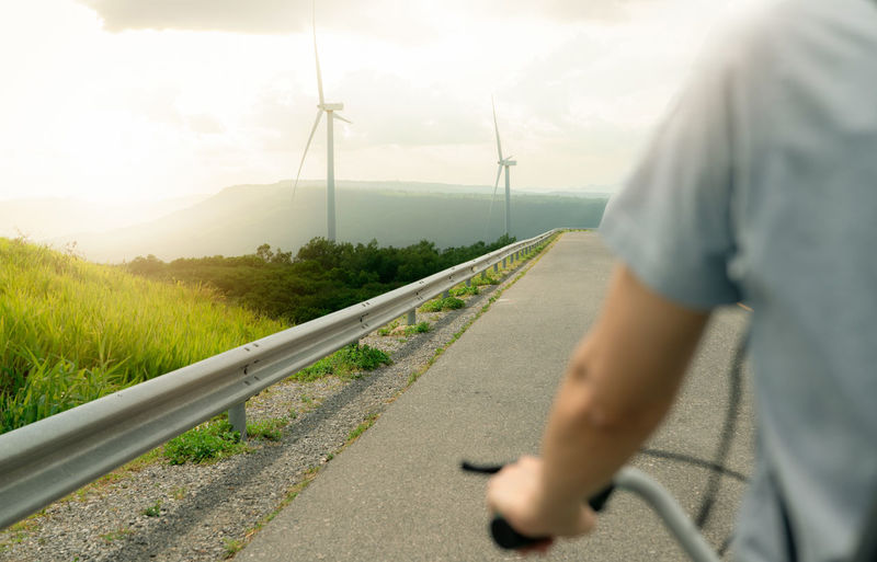 Low section of man walking on road against sky