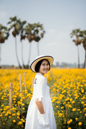 Woman standing by yellow flowers on field