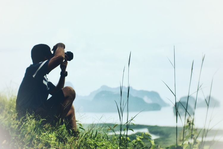 Man photographing woman on grass
