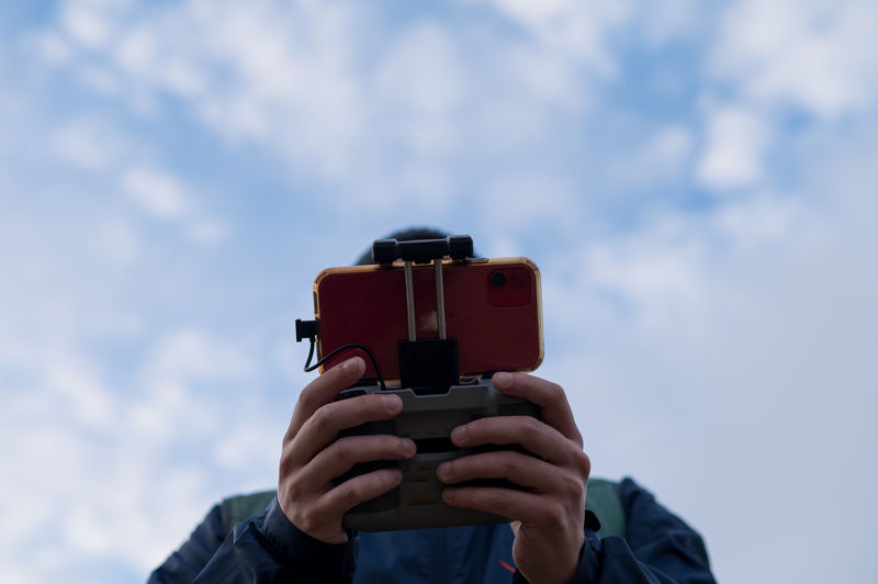 Man photographing with camera against sky