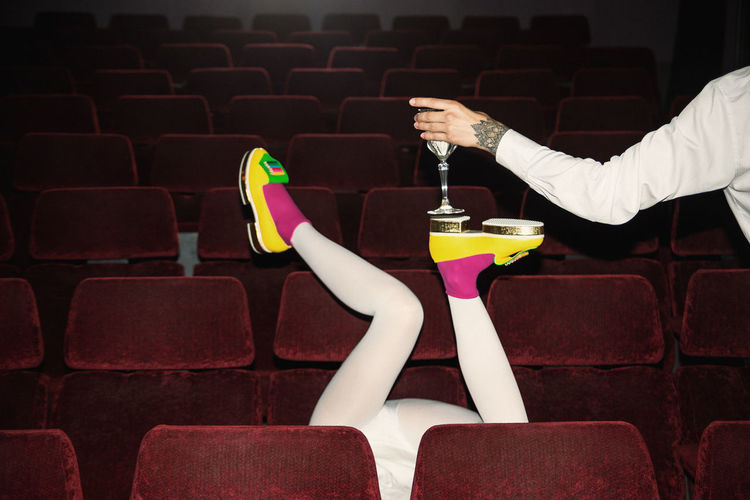 Low section of person serving wine to man in theater