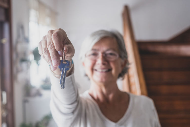 Portrait of senior woman holding key at home