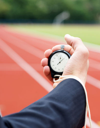 Time is running - businessman in stadium holds stopwatch in his hand - close-up