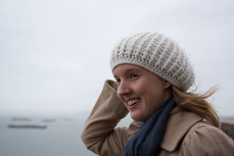 Portrait of smiling young woman against sky during winter