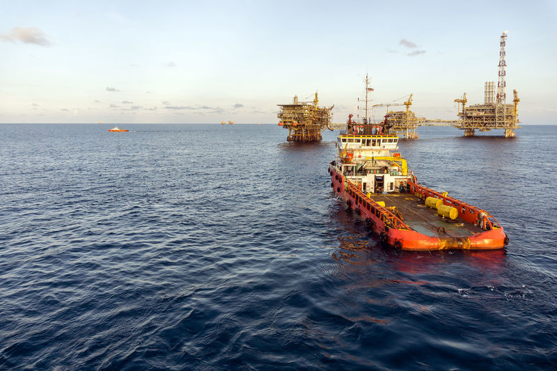 An anchor handling tug boat maneuvering at offshore oil production platform 