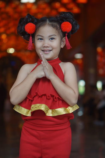 Portrait of happy girl holding red while standing against blurred background