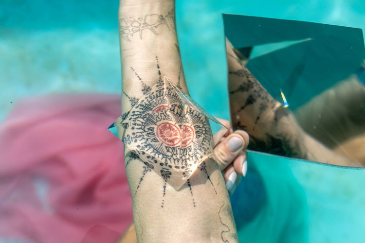 Cropped image of woman with prism on tattoo underwater