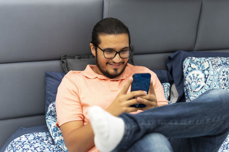 Midsection of man using mobile phone while sitting on sofa
