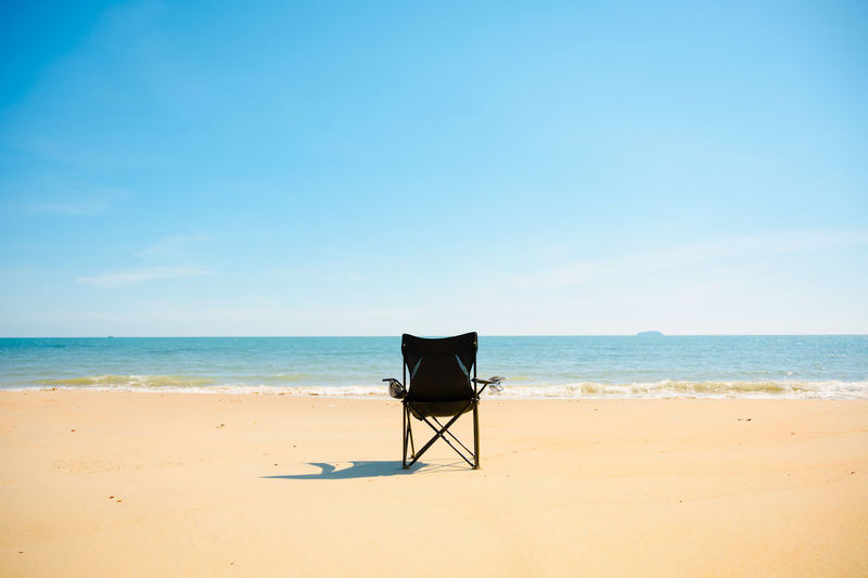 Lifeguard chair on beach against blue sky