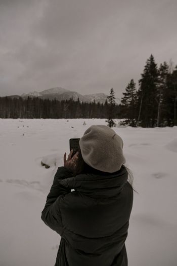 Rear view of man photographing against sky during winter